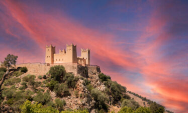 Ancient Moroccan castle glowing under a pink-orange sky