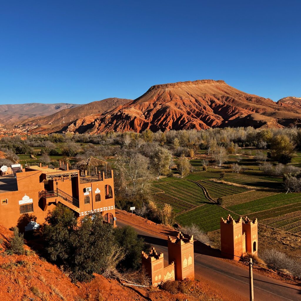 Village with reddish hills and mountains in the background