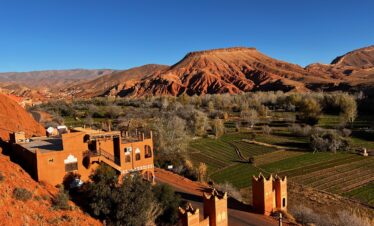 Village with reddish hills and mountains in the background