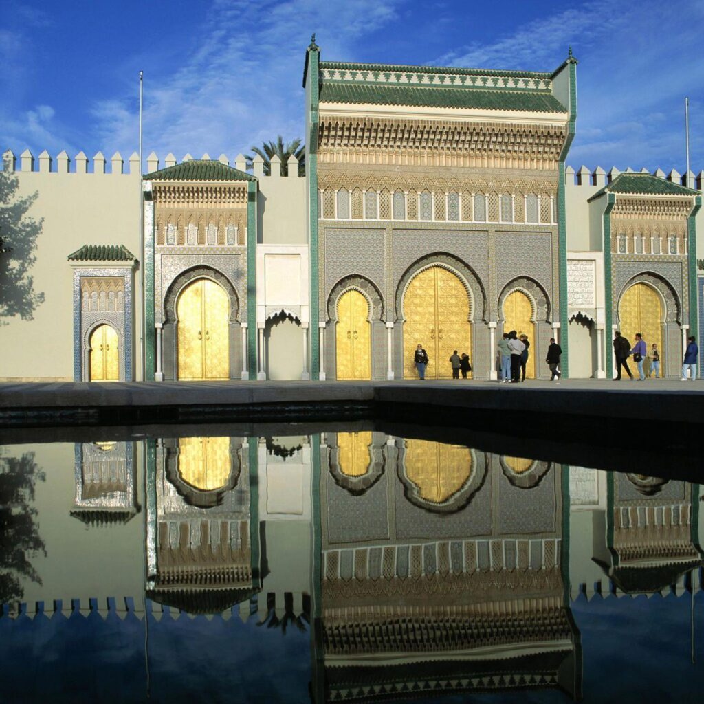 Night-time view of a lit Moroccan mosque mirrored in water