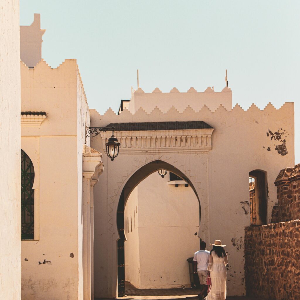 Woman in white dress standing in a blue Chefchaouen alleyway