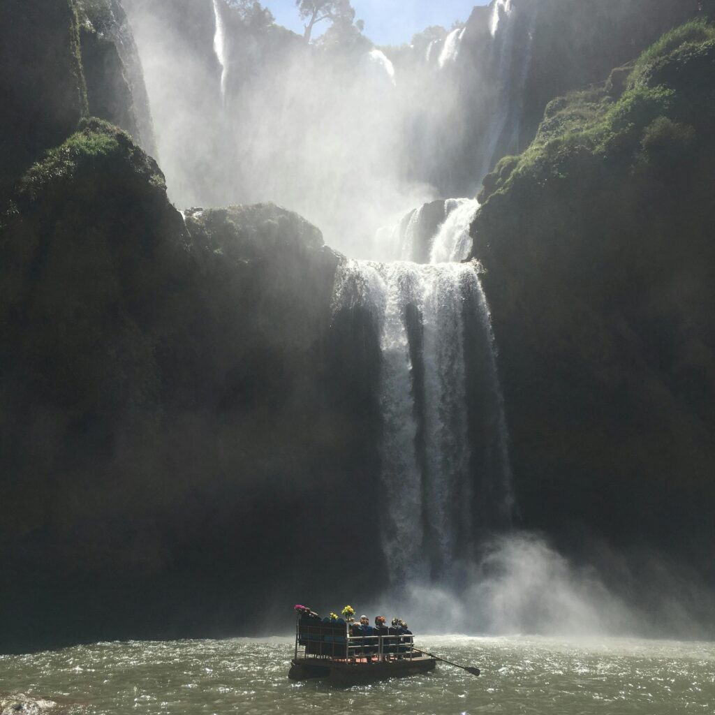 Tall waterfall plunging into a pool with a boat below