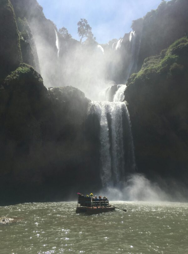 Tall waterfall plunging into a pool with a boat below