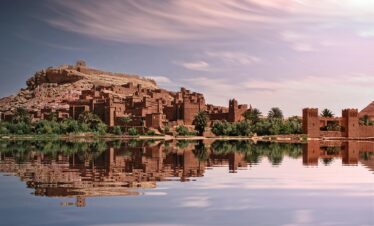 Moroccan kasbah mirrored in still waters during sunset