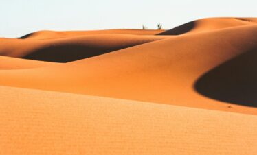Lone traveler walking across orange Moroccan dunes