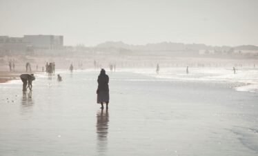 Lone figure walking along a foggy beach or tidal flat