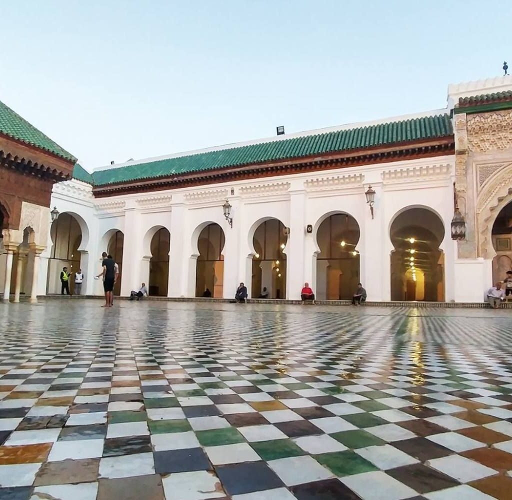 Moroccan mosque courtyard featuring tiled floor and arched colonnades