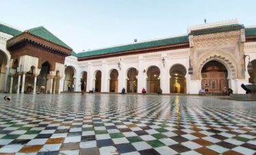 Moroccan mosque courtyard featuring tiled floor and arched colonnades