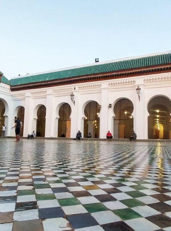 Moroccan mosque courtyard featuring tiled floor and arched colonnades