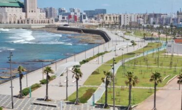 Curved coastal walkway near beach and towers