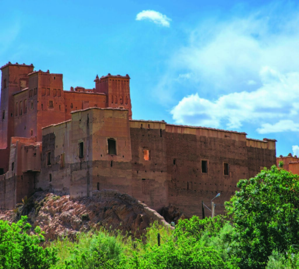 Red Moroccan kasbah surrounded by trees