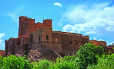 Red Moroccan kasbah surrounded by trees
