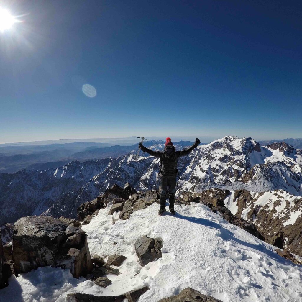 Man raising arms on snowy mountain top