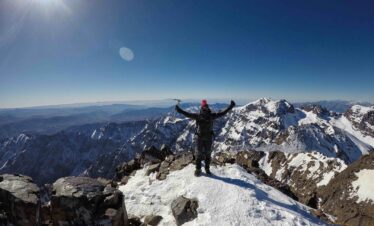 Man raising arms on snowy mountain top