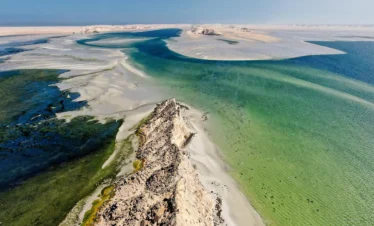 Golden sand dunes fading into turquoise ocean