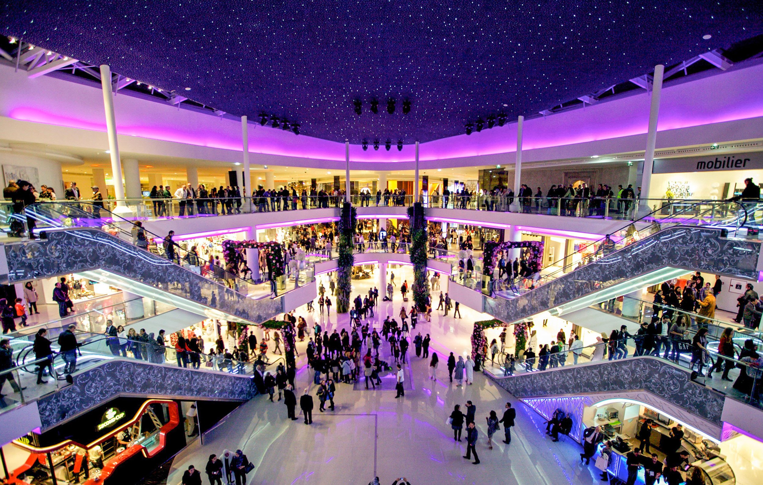Purple ceiling lights over shopping crowds