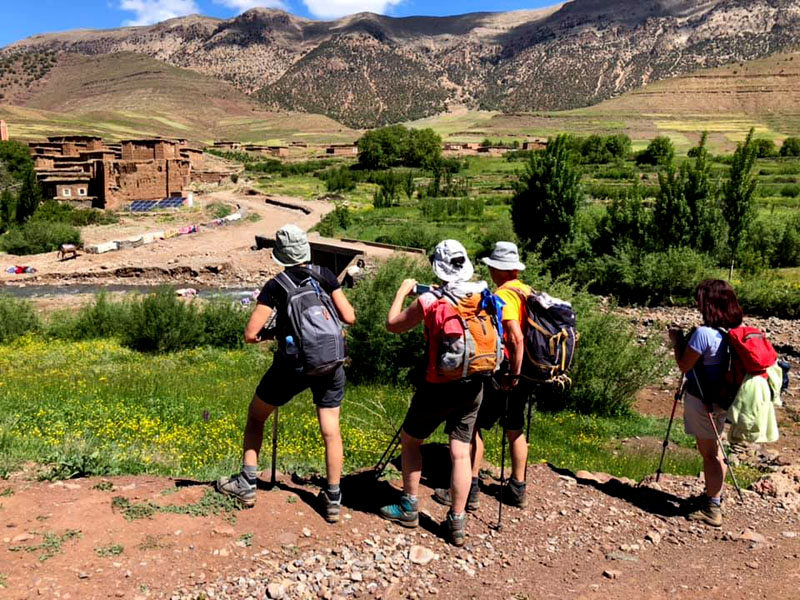 Two hikers walking on a rugged trail in the Atlas foothills.