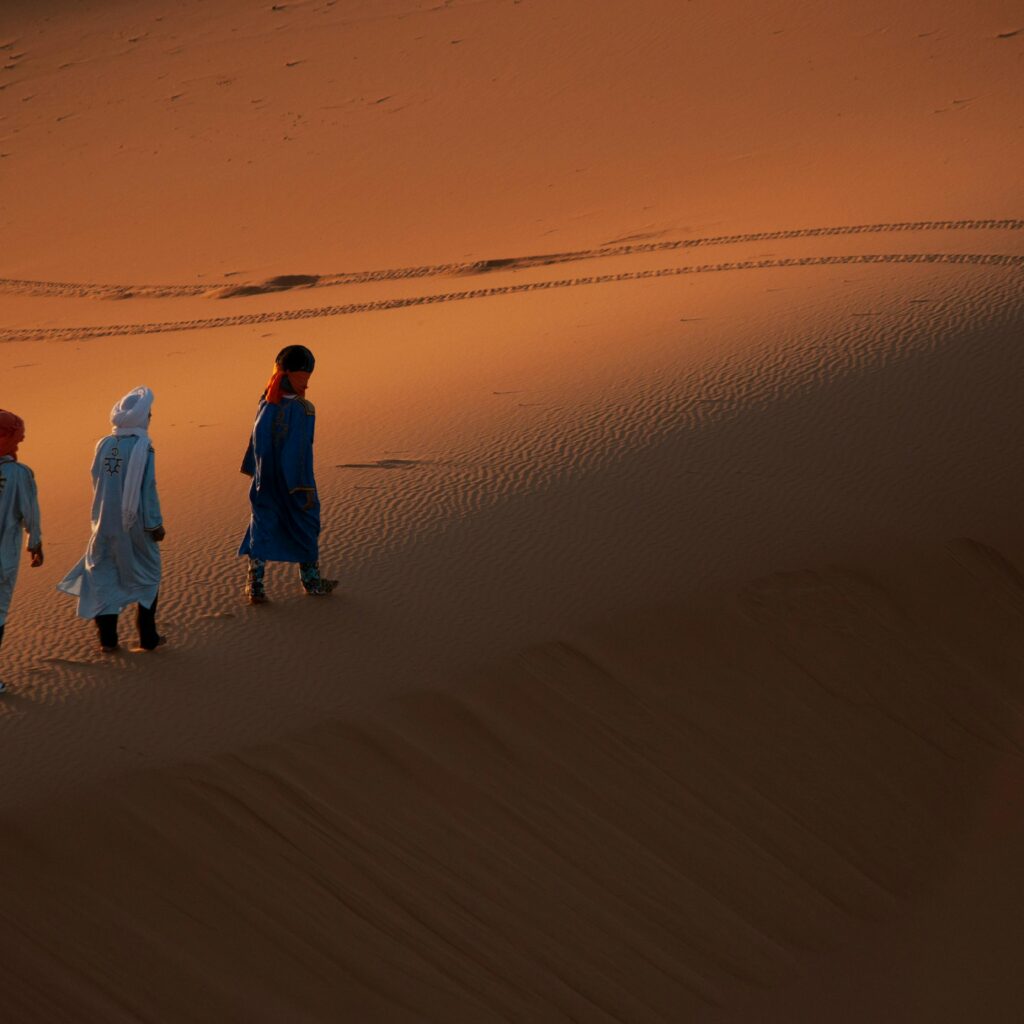 People walking through desert dunes