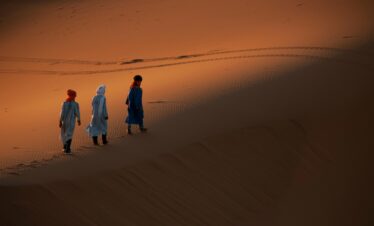People walking through desert dunes