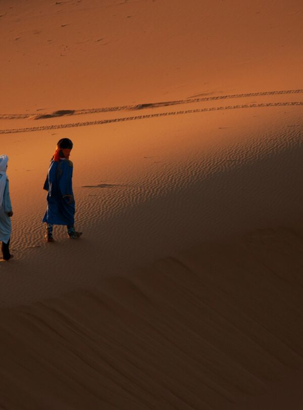 People walking through desert dunes