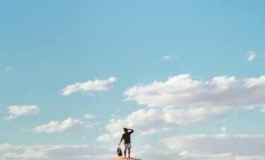 Person standing alone in vast orange dunes
