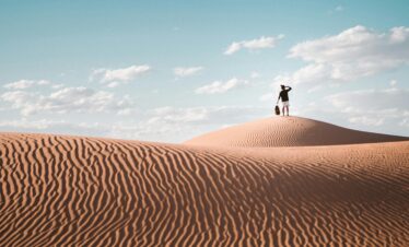 Person standing on a sand dune under clear sky