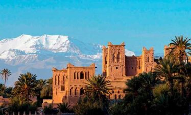 Snow-capped mountains behind a Moroccan kasbah