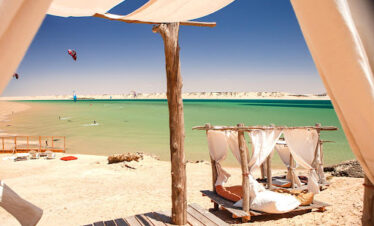 Two beach chairs under a parasol near the sea