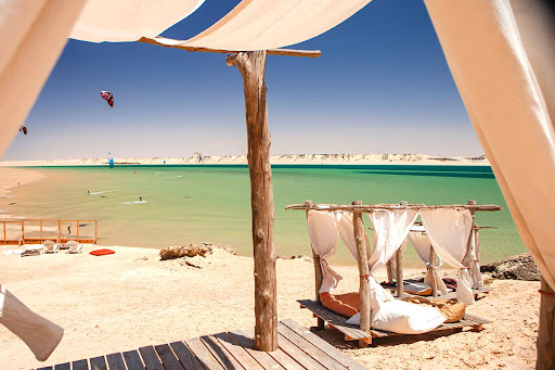 Two beach chairs under a parasol near the sea