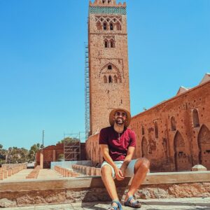 Study Abroad Morocco Man in hat sits near koutoubia mosque in marrakech.