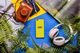 eSIM A book, headphones, a camera, and a cell phone on a table