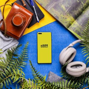 eSIM A book, headphones, a camera, and a cell phone on a table