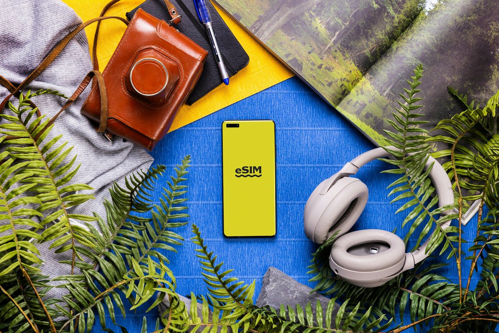 eSIM A book, headphones, a camera, and a cell phone on a table