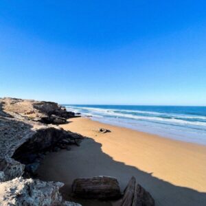 Coastal Road Trip Morocco a sandy beach with rocks and water on a sunny day