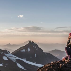 Breathtaking Sunsets a woman sitting on top of a mountain next to snow covered mountains
