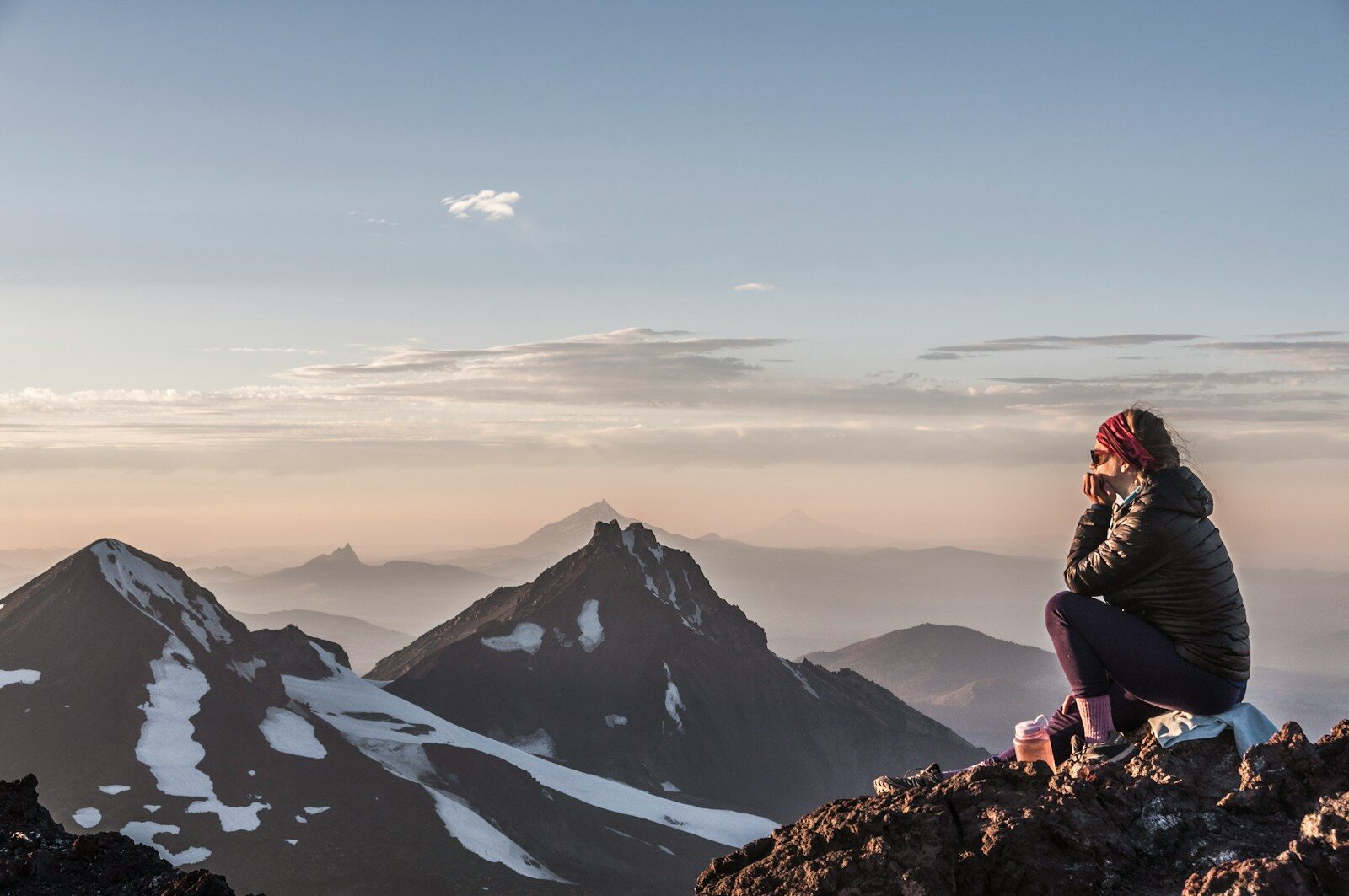 Breathtaking Sunsets a woman sitting on top of a mountain next to snow covered mountains