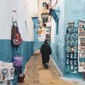 Photography person wearing hooded jacket walking on alley between buildings during daytime