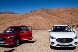 Driving in Morocco Two cars parked in a dry, mountainous landscape.