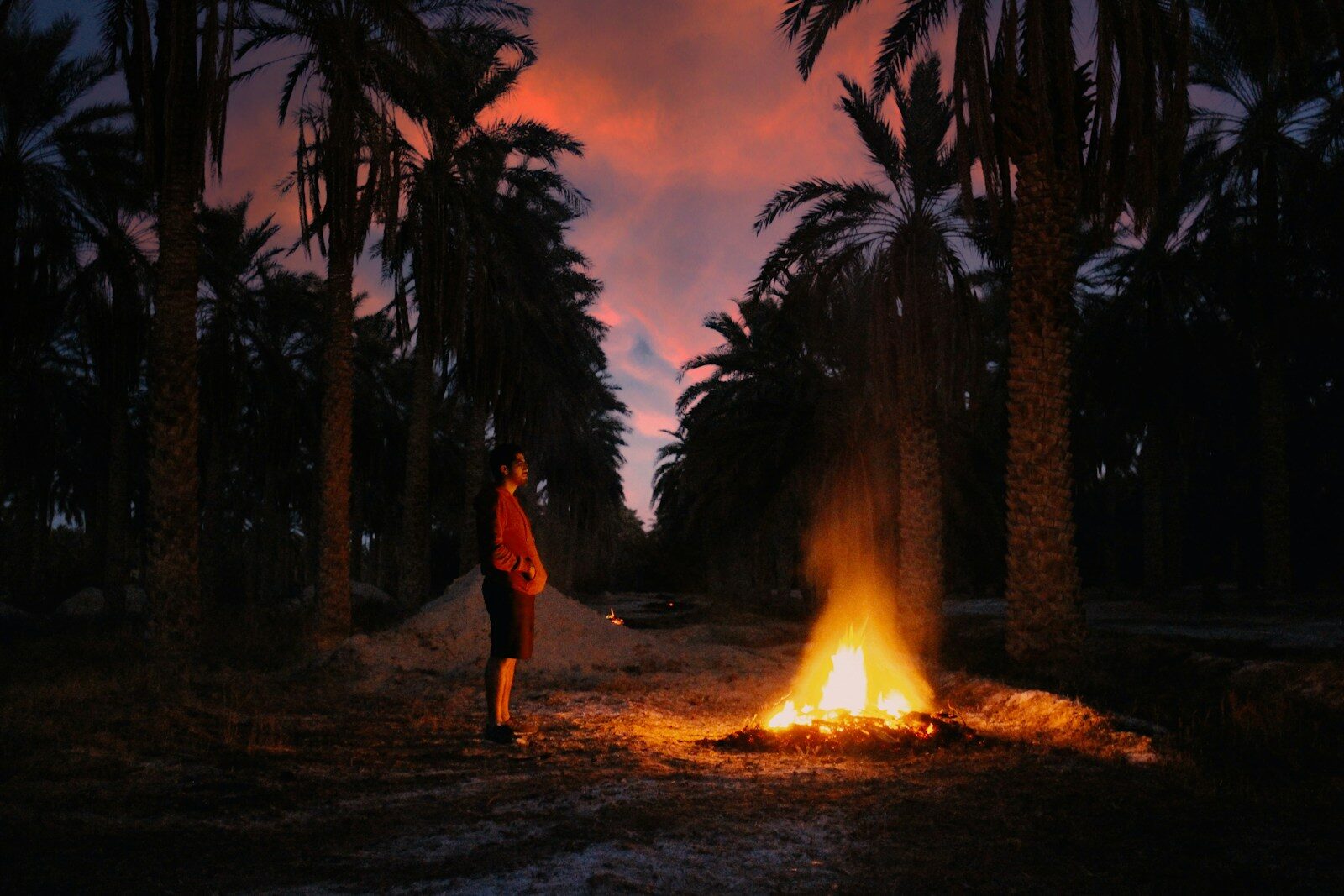Sahara Photography man in red jacket standing near bonfire during night time