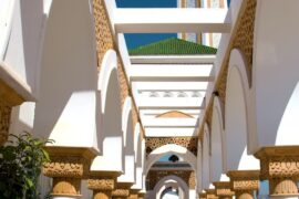 Tangier A walkway lined with columns and arches with a clock tower in the background
