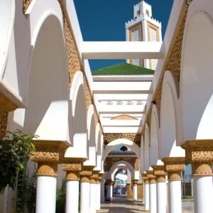 Tangier A walkway lined with columns and arches with a clock tower in the background