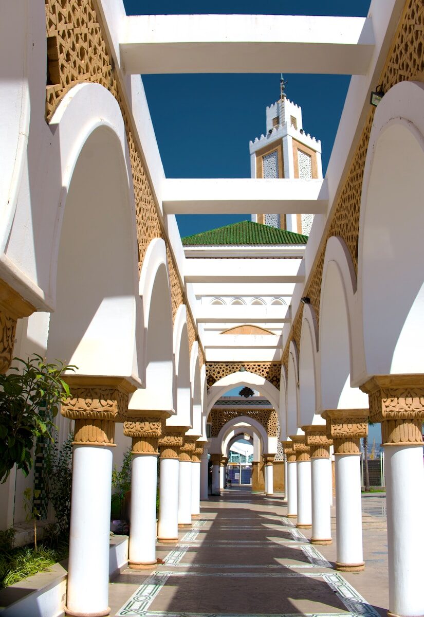Tangier A walkway lined with columns and arches with a clock tower in the background