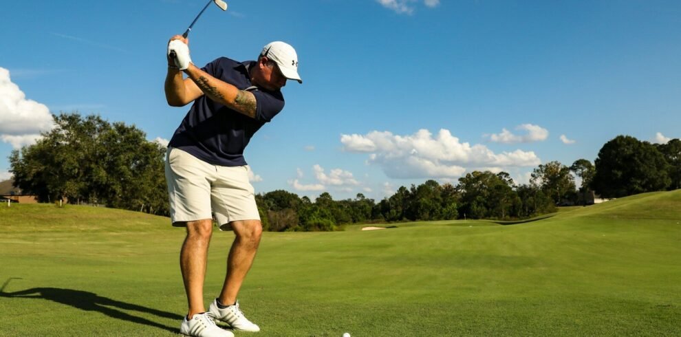 man in black shirt and white shorts playing golf during daytime