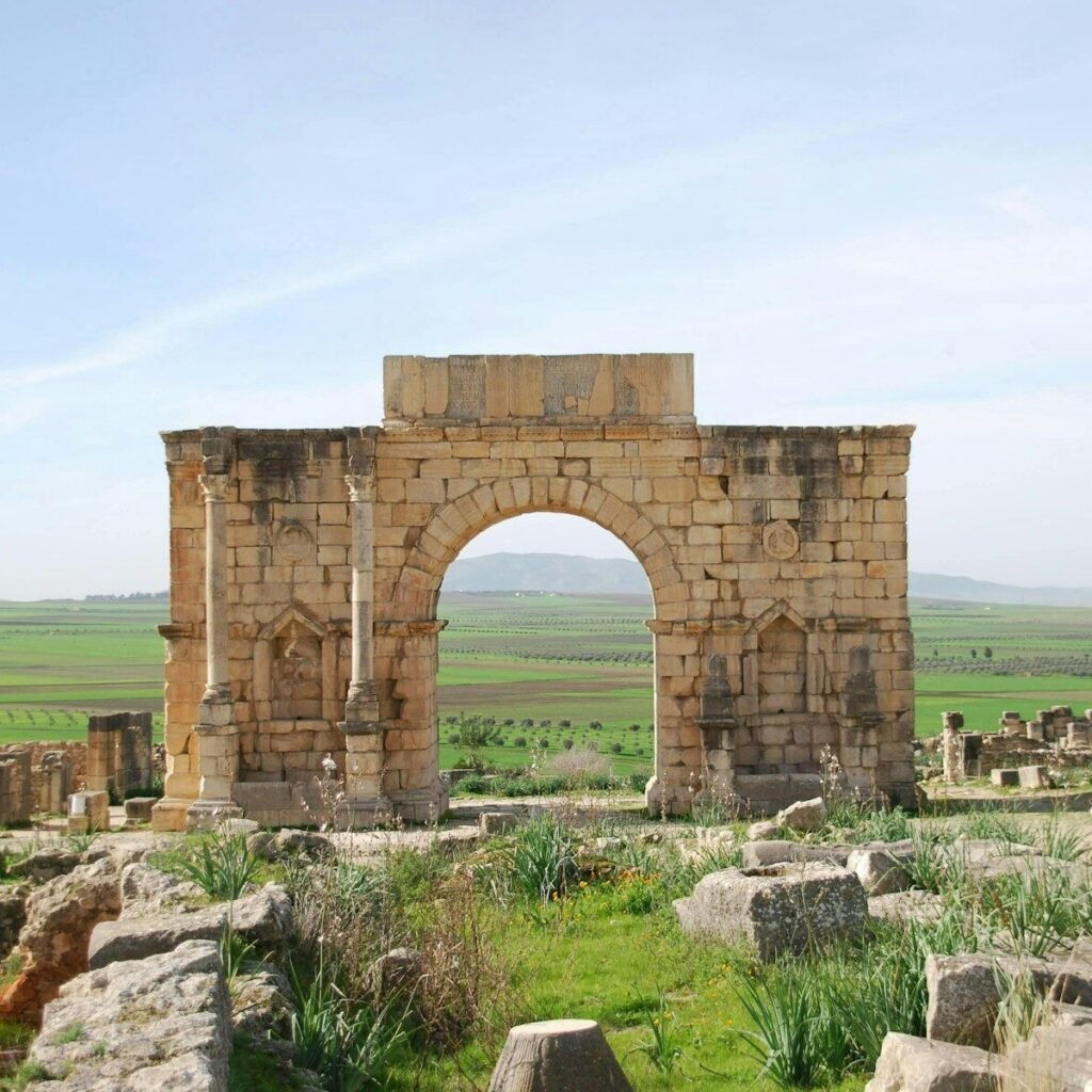 A stone arch in the middle of a field