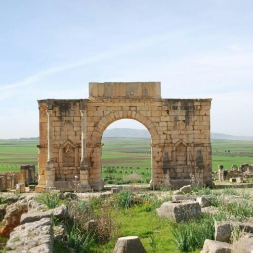 A stone arch in the middle of a field