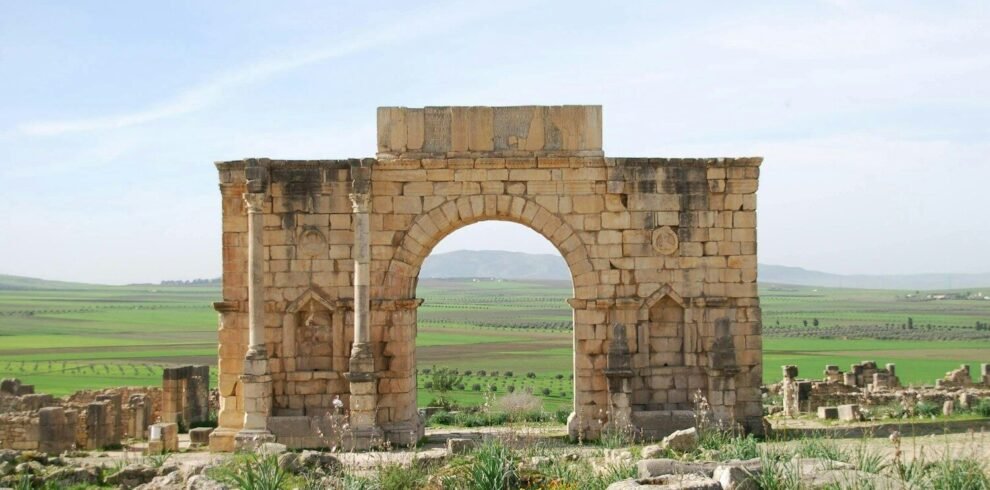 A stone arch in the middle of a field