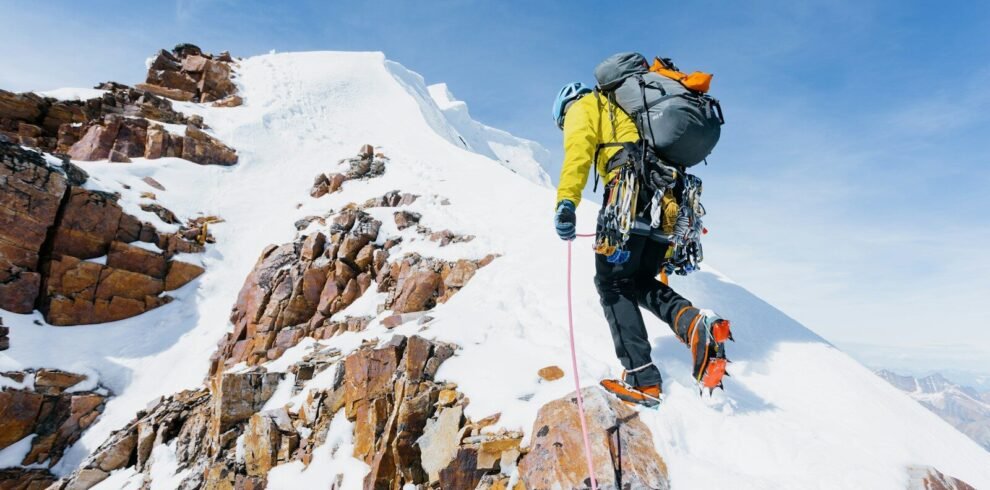 a man climbing up the side of a snow covered mountain