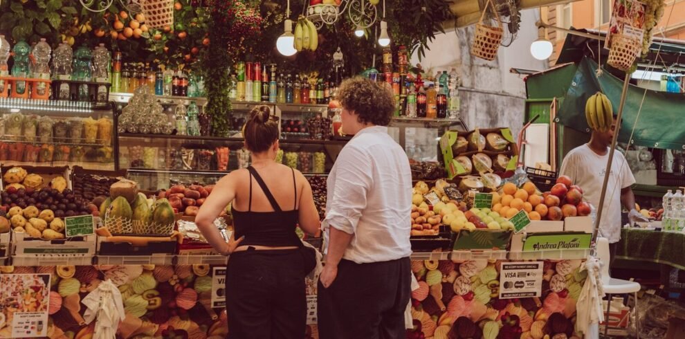 People browsing a vibrant fruit and vegetable market stall.