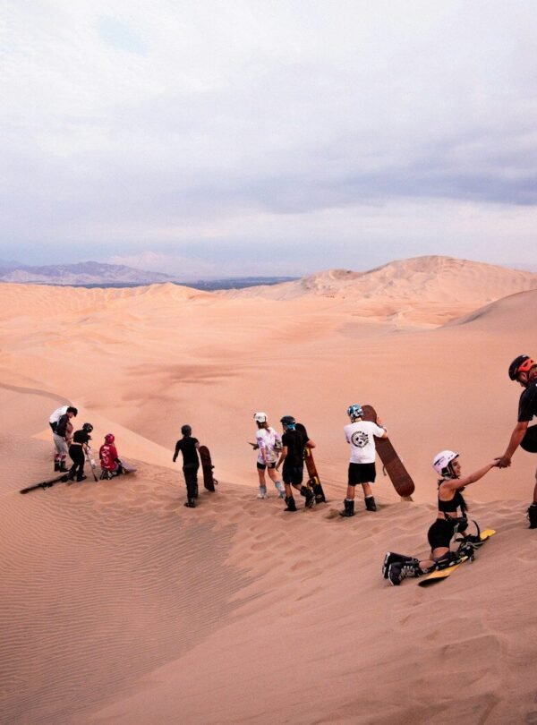 a group of people standing on top of a sand dune