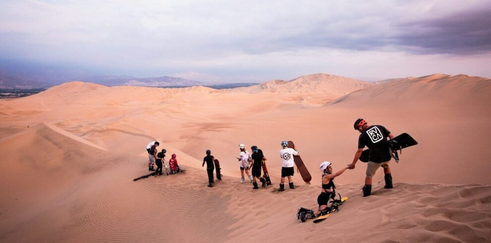 a group of people standing on top of a sand dune